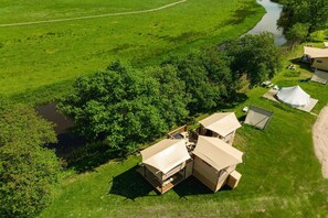 Ein Campingplatz mit mehreren Zelten und einem Holzbau mit einer Terrasse.