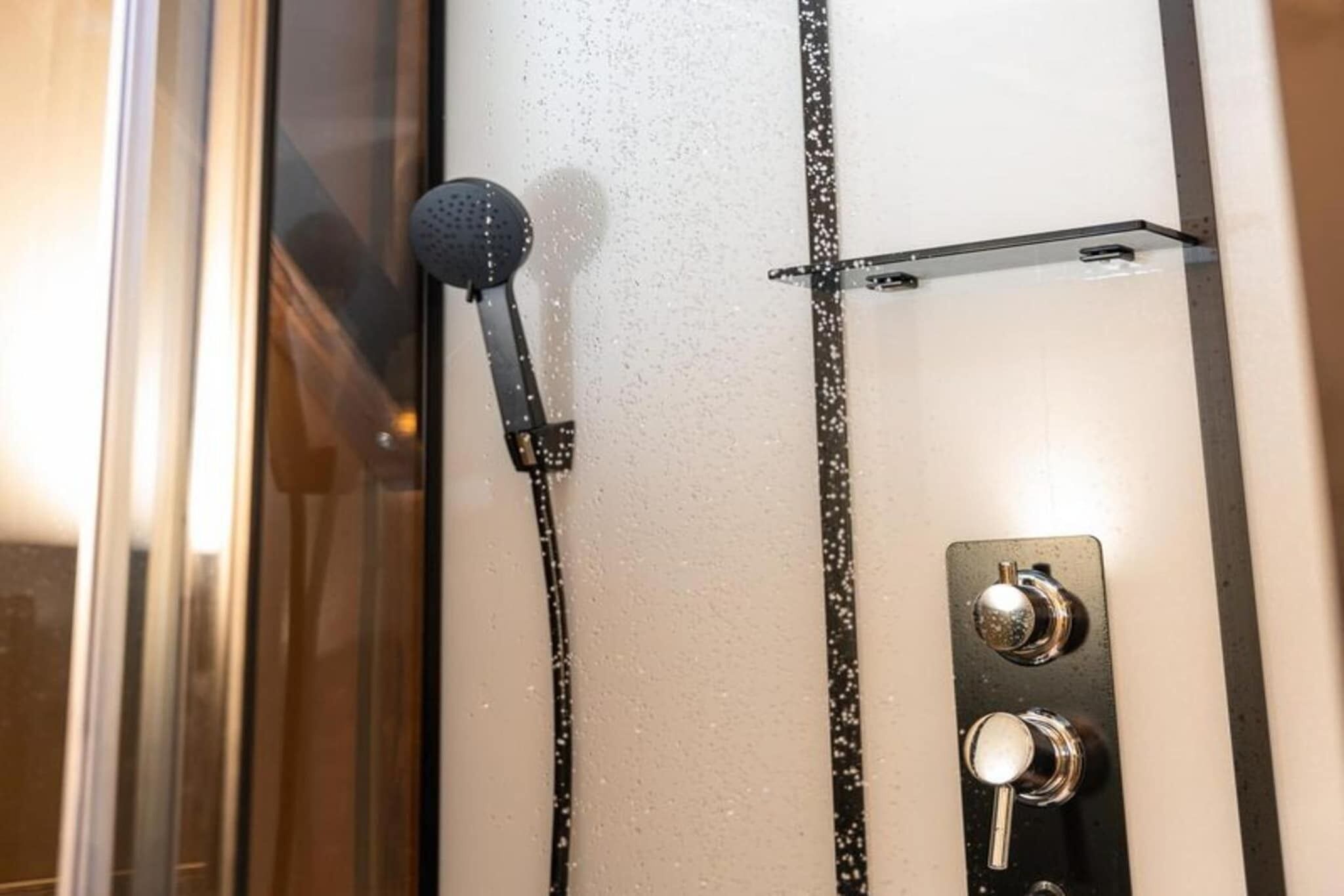 A shower with a handheld showerhead and control knobs.