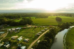 Vista aérea de una propiedad rural con varias construcciones, un río y campos verdes.