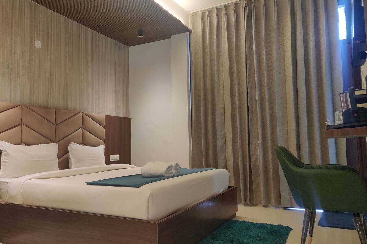 Una habitación de hotel con una cama, un escritorio con una silla, un ventilador de techo y cortinas.