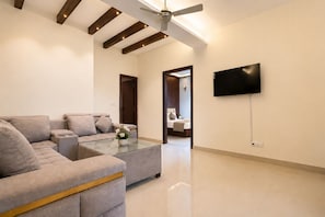 A modern living room with a sofa, coffee table, and a flat-screen TV mounted on the wall. - Hotel Heaven & Hills Kasauli (Kasauli)