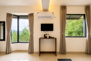 A room with a flat-screen TV mounted on the wall, a small table with a coffee maker, and an air conditioning unit. - Hotel Heaven & Hills Kasauli (Kasauli)