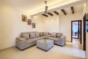 Ein modernes Wohnzimmer mit einem Ecksofa, einem Glastisch und einem Deckenventilator.