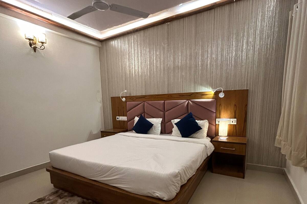 Un dormitorio ordenado con una cama grande, cabecera de madera, lámparas de noche, una alfombra mullida y un ventilador de techo.