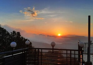 A sunset view from a balcony with railings and spherical light fixtures. - Hotel Heaven & Hills Kasauli (Kasauli)