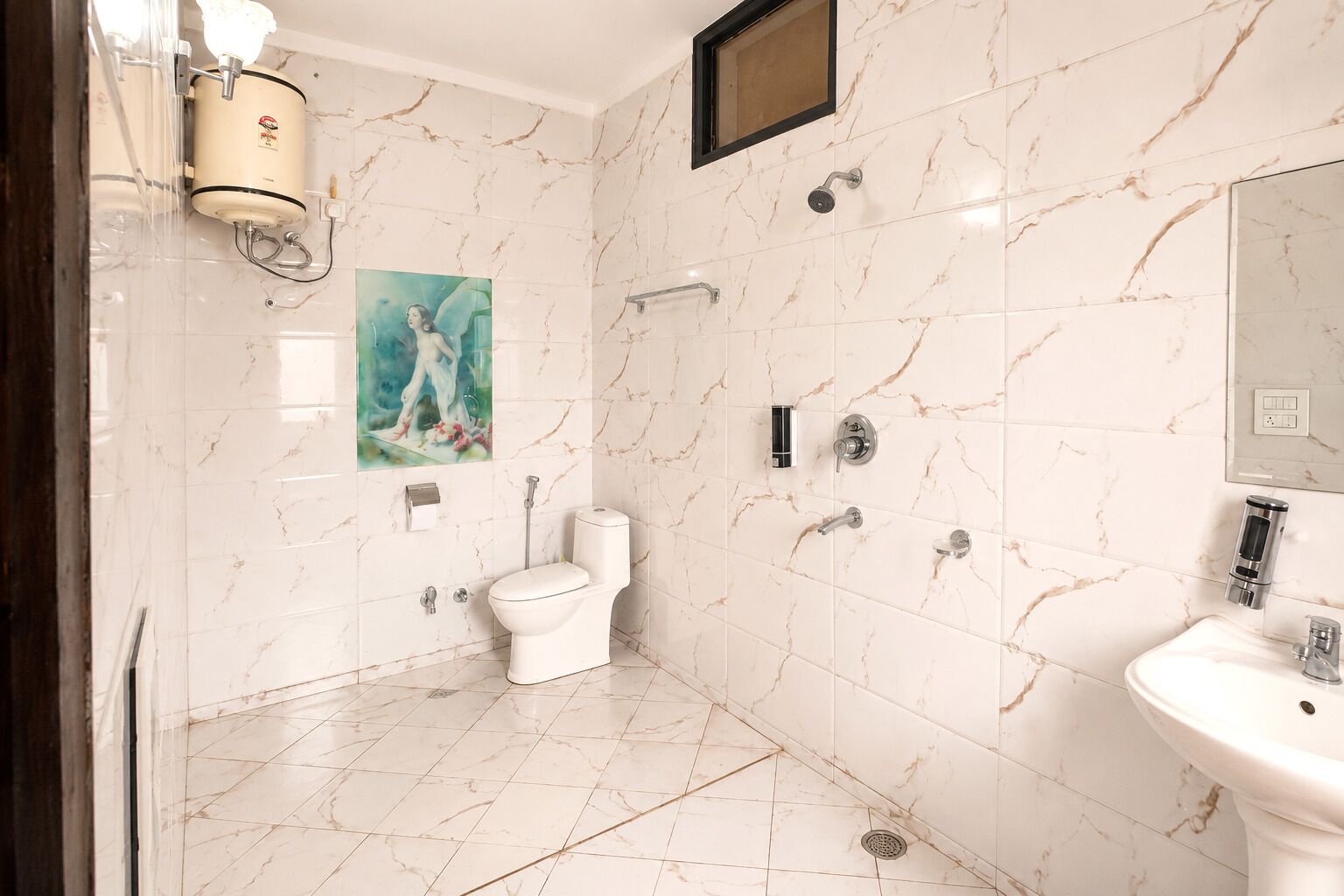 A bathroom with a toilet, shower, sink, and a marble wall.
