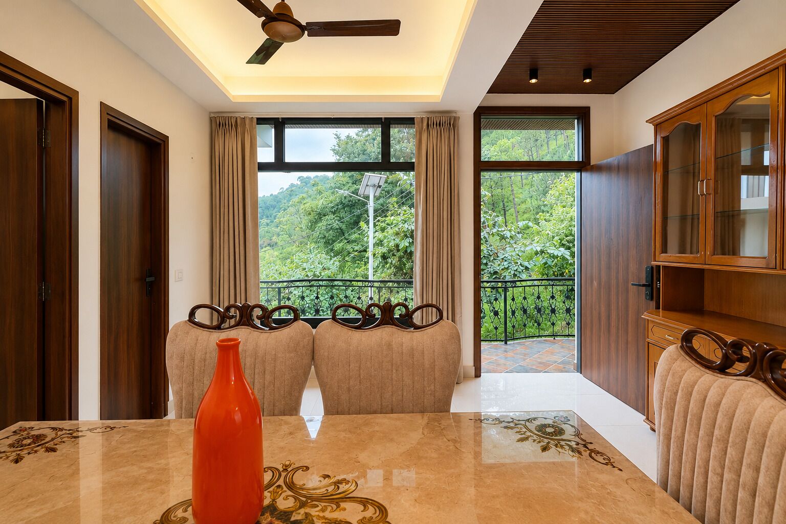 A room with a large window, a ceiling fan, and a wooden cabinet.