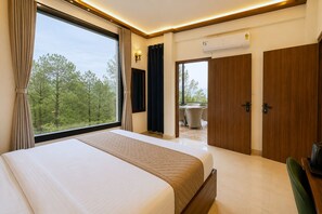 Quarto de hotel com uma cama grande, vista para o exterior, varanda e porta que dá para outro cômodo.