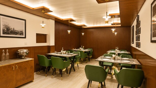 Un espace repas comprenant plusieurs tables et chaises, des lambris en bois aux murs et un éclairage suspendu.