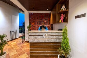 A reception desk with a 'RECEPTION' sign, a check-out time sign, and a statue on the wall. - Hotel Heaven & Hills Kasauli (Kasauli)