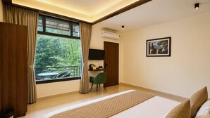Une chambre d’hôtel avec un lit, un bureau, une chaise, une fenêtre avec des rideaux et un tableau au mur.