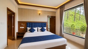 Une chambre moderne avec un grand lit, une tête de lit en bois, des tables de chevet et une vue sur la verdure par la fenêtre.