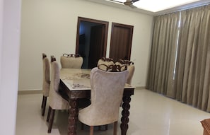 Un comedor con una mesa rectangular, seis sillas tapizadas y un ventilador de techo.