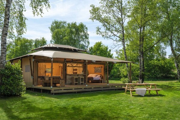 Una cabaña de madera con un porche, una mesa de comedor y una mesa de picnic.