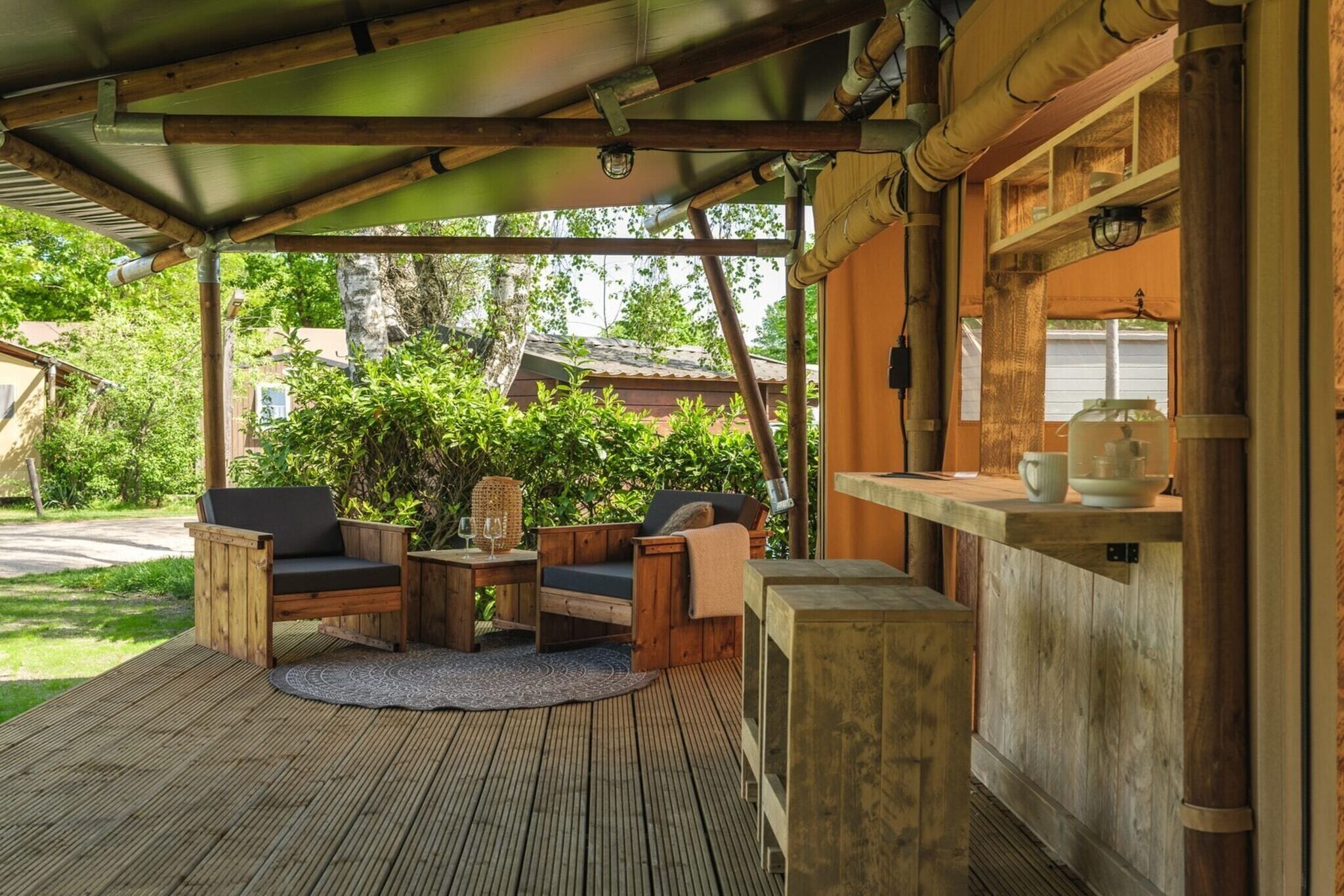 Un espace extérieur abrité, aménagé avec du mobilier en bois, une table ronde et un comptoir de bar.