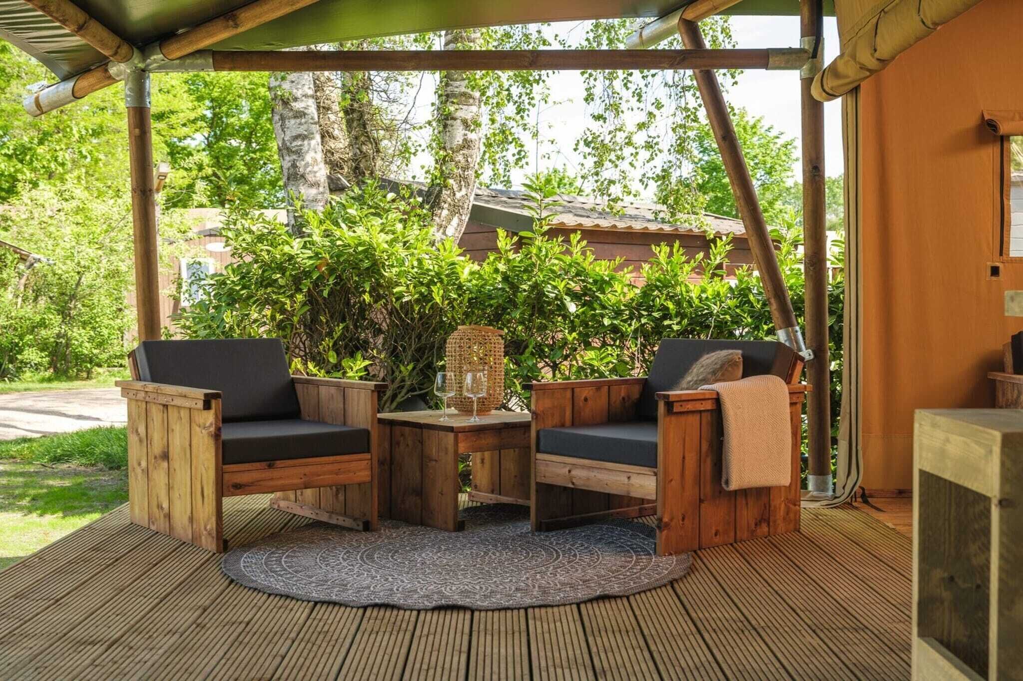A wooden deck with two chairs and a table, a woven basket, and a glass of wine.
