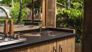 A kitchen with a wooden countertop, a sink, and a stove. - Charming Safari Tent for Family Glamping (Zuna)