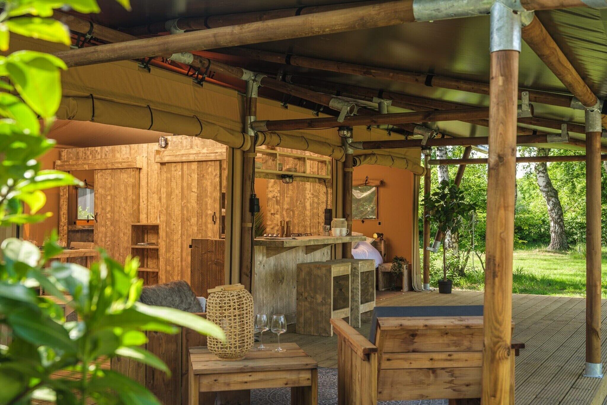 A rustic wooden structure with a covered outdoor seating area, a wooden counter, and a view of a green landscape.