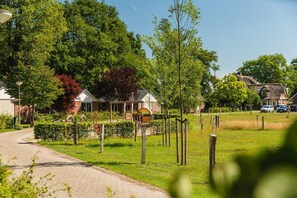 A rural setting with a paved path, wooden fences, and a small building with a thatched roof. - Bungalow with Nursery and Playground (Zuna)