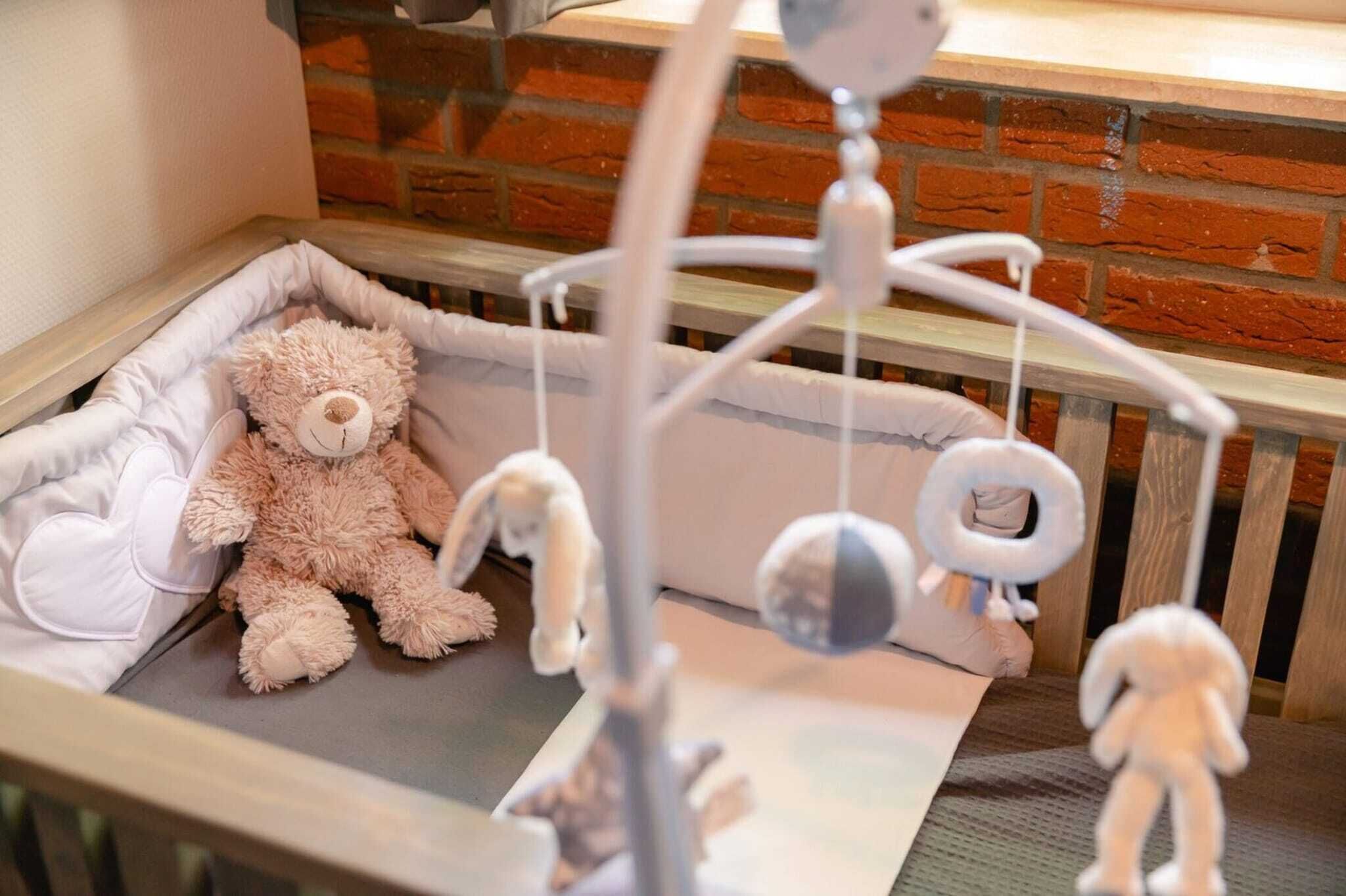 Un berceau avec un ours en peluche, un mobile suspendu et un oreiller blanc.