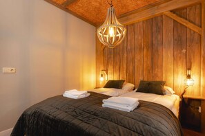 Een kamer met twee bedden, houten wanden en een hanglamp.