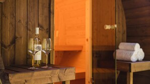 A wooden interior with a table holding a bottle and two glasses. - Six-Person Wellness Farmhouse (Zuna)