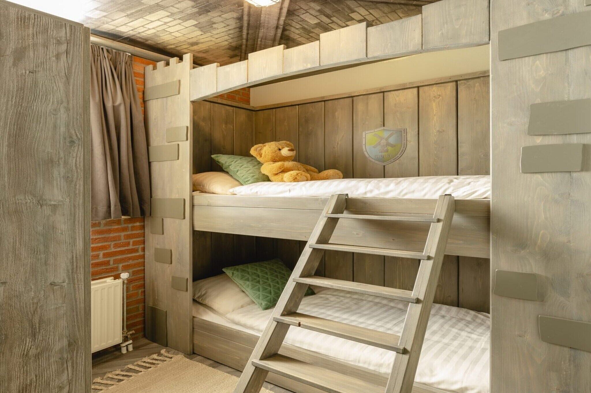 A bunk bed room with a ladder, wooden walls, and a teddy bear on the top bunk.