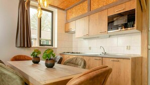 A modern kitchen with wooden cabinets, a dining table with chairs, and potted plants.