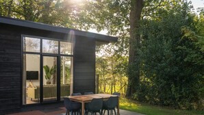 A modern house with a patio, a dining table, and chairs. - Luxury Family Lodge with Hot Tub (Zuna)