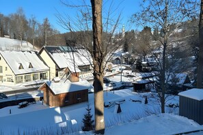 Ein verschneites Dorf mit traditionellen Holzhäusern, einer Kirche und einem strahlend blauen Himmel.