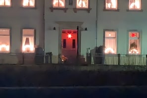 Ein Gebäude mit mehreren Fenstern, von denen einige mit Vorhängen versehen sind, und einer Zargendose mit einer Sterndekoration.