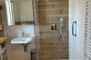 Ein modernes Badezimmer mit einem weißen Waschbecken, Spiegel und Dusche.