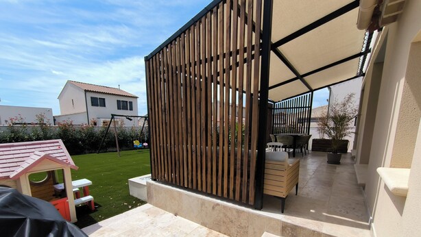 A covered patio area with a wooden fence, outdoor seating, and a small playhouse.