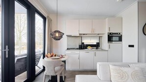 Une cuisine moderne avec des meubles blancs, un coin repas comprenant une table et des chaises, et un canapé.