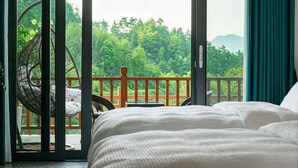 A bedroom with a bed, a chair, and a view of a balcony with a railing. - Shiyi Tangwan Yangjiajie Lodge (Zhangjiajie)