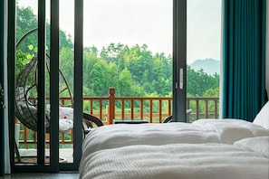 Ein Schlafzimmer mit Bett, Stuhl und Blick auf einen Balkon mit Geländer.