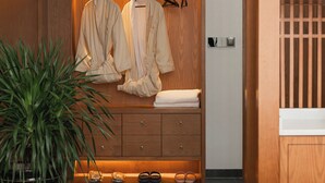 A wooden wardrobe with hanging robes, a folded robe, and a towel on top. - Shiyi Tangwan Yangjiajie Lodge (Zhangjiajie)