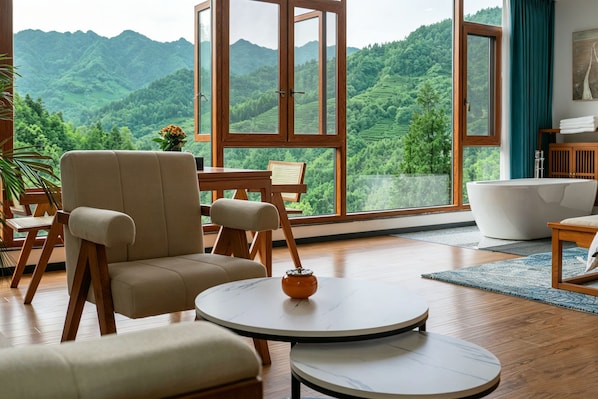 A room with a large window, a bathtub, a round table, and a sofa. - Tangwan Mountain Homestay - Yangjiajie (Zhangjiajie)