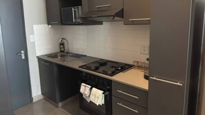 Una cocina moderna con microondas, estufa, horno y armarios oscuros.