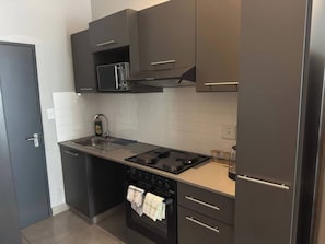 Eine moderne Küche mit Mikrowelle, Herd, Backofen und dunklen Schränken.