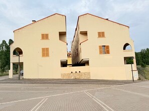 A symmetrical building with two wings, each featuring a balcony and a small window.