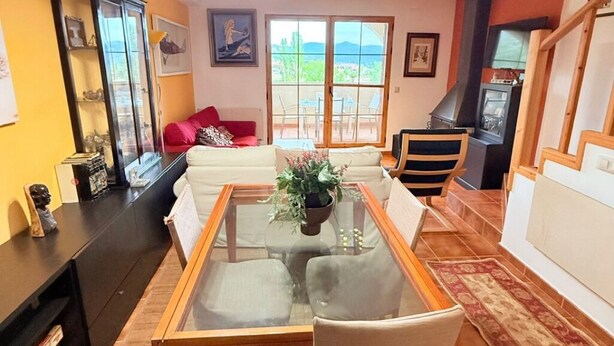 A living room with a glass-top coffee table, a sofa, a fireplace, and a view through large windows.