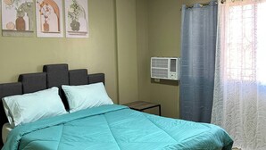 Een slaapkamer met een bed, nachtkastje, een wandairconditioner en een raam met gordijnen.