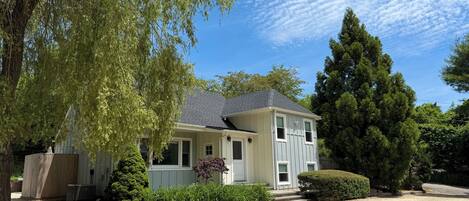 A two-story house with a gravel driveway, surrounded by trees and a well-maintained lawn.