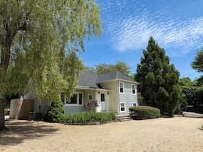 A two-story house with a gravel driveway, surrounded by trees and a well-maintained lawn. - Peaceful and Private 4-Bedroom Home in Southampton (Southampton)