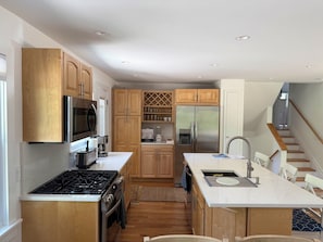 A modern kitchen with wooden cabinets, stainless steel appliances, and a central island with a sink. - Peaceful and Private 4-Bedroom Home in Southampton (Southampton)