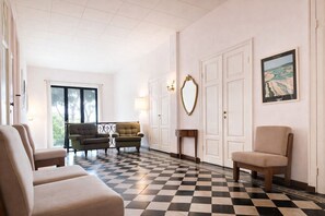 Un vestíbulo de hotel con suelo a cuadros, dos sillones, un sofá, un espejo y una lámpara.