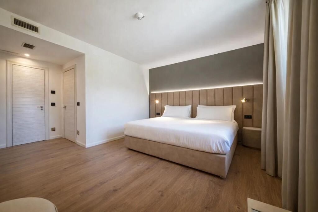 Una habitación de hotel moderna con una cama grande, una mesita de noche, un armario y una lámpara de techo.