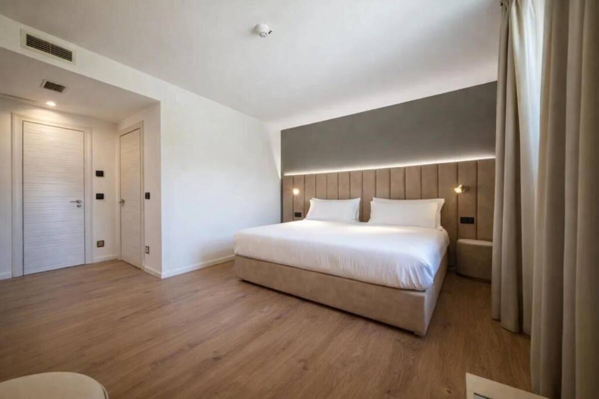 Una habitación de hotel moderna con una cama grande, una mesita de noche, un armario y una lámpara de techo.