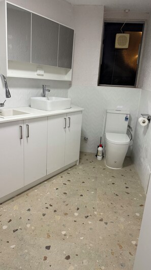 Un baño con lavamanos, espejo y retrete blancos.